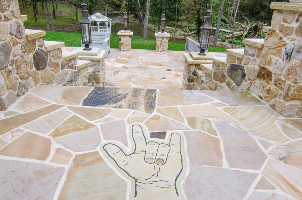 A stone patio with an engraved hand-language sign that means “I Love You” in the patio.