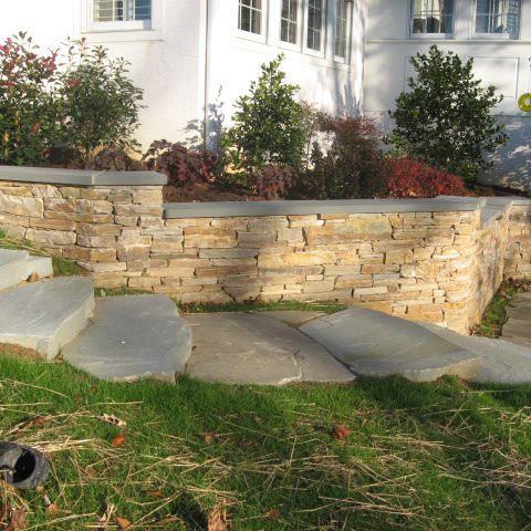 Wide stone stairs with a veneer stone sitting wall.