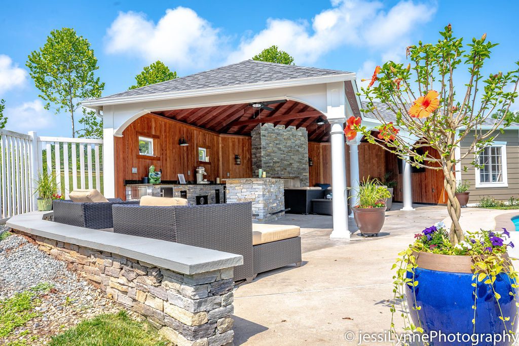A beautiful natural stone outdoor kitchen by Dutchies Stoneworks is protected from the elements with a complete roof.