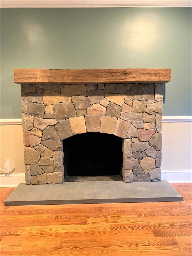 A flagstone hearth, stone surround, and wood mantle fireplace in a home.