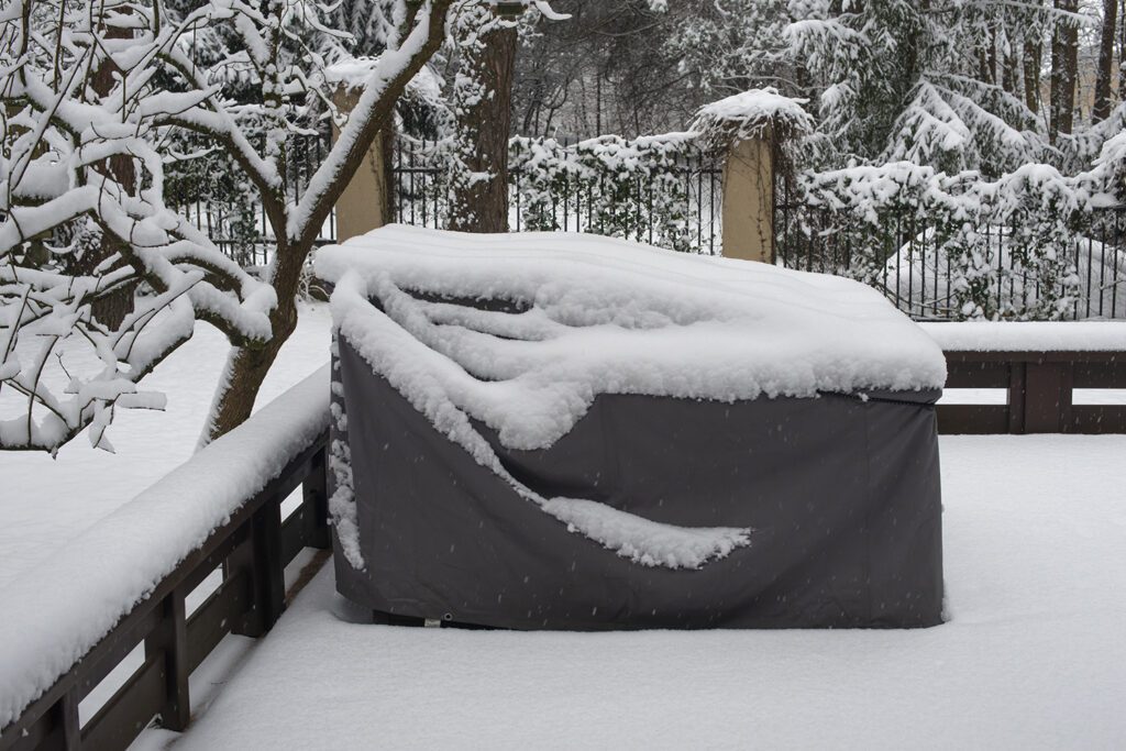 Outdoor patio furniture is protected from falling snow with a waterproof furniture cover.