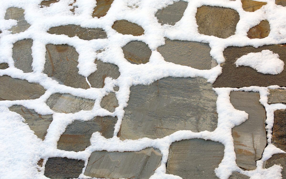 Snow covers a natural flagstone patio.