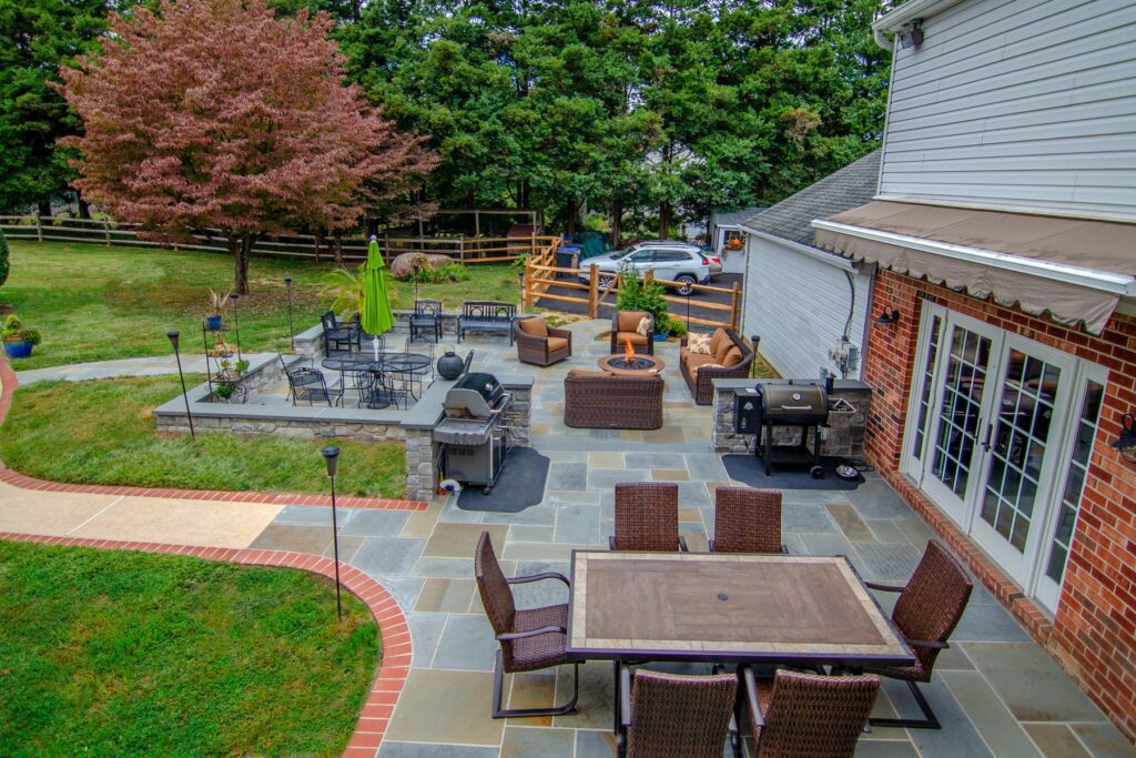 A natural stone patio with a grill, smoker, and multiple seating areas.