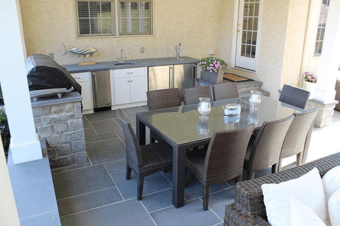 A covered outdoor kitchen with stone flooring.